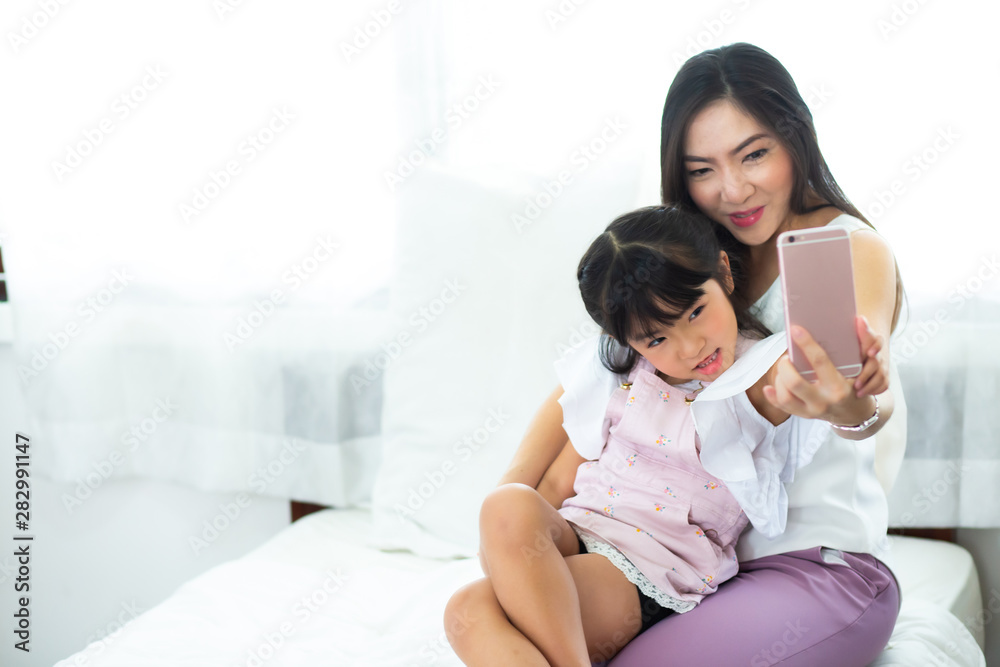beautiful mother and her daughter making a selfie using smart phone and smiling beautiful mother and her daughter making a selfie using smart phone and smiling