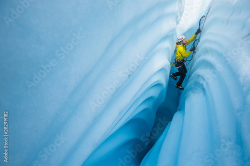 Ice climbing between canyon walls covered in wavy lines carved by meltwater. photo