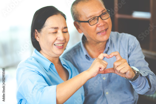 Love forever! Asian Senior couple at home and showing heart gesture with two hands