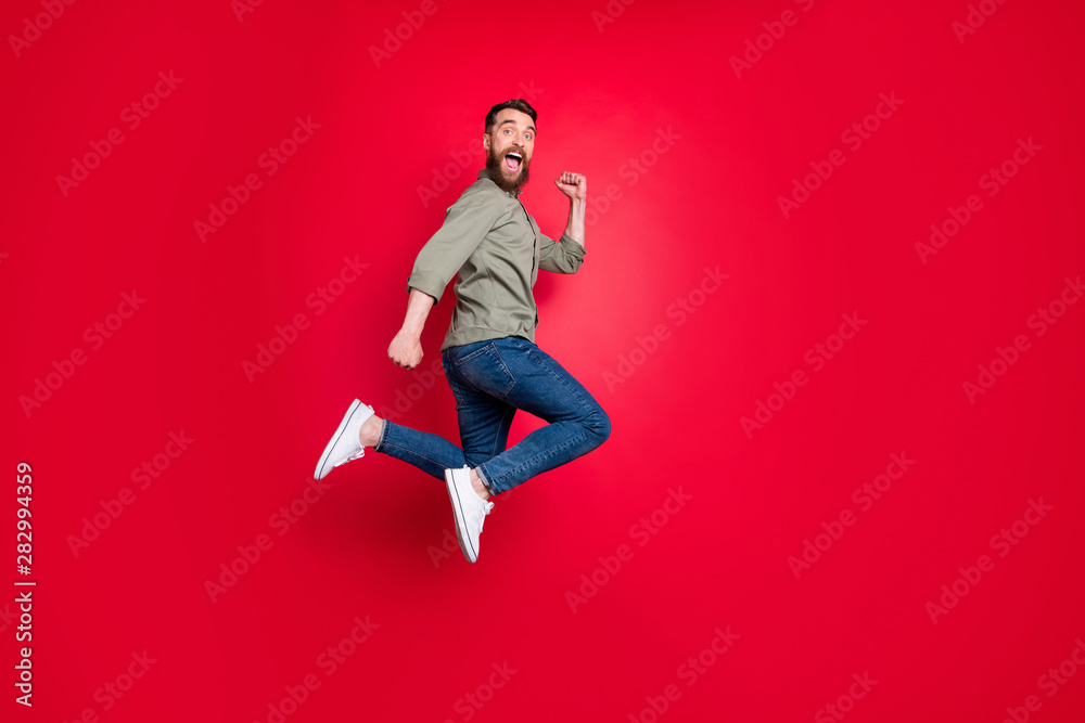 Full length body photo of man having decided to do sport and started running while isolated with red background