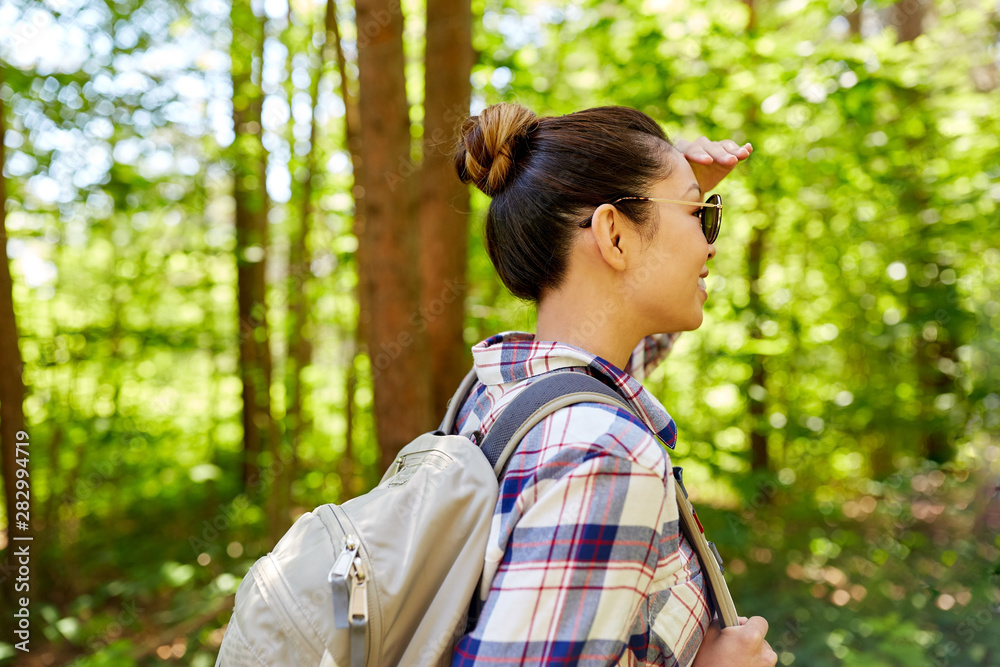 travel, tourism, hike and people concept - happy asian woman with backpack looking far away in forest travel, tourism, hike and people concept - happy asian woman with backpack looking far away in forest