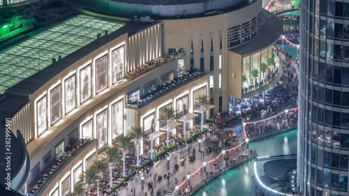 Lots of tourists walking near foutains and shopping mall in Dubai downtown night timelapse. Aerial view to one of the largest shopping malls in the world. Balcony with viewpoint photo