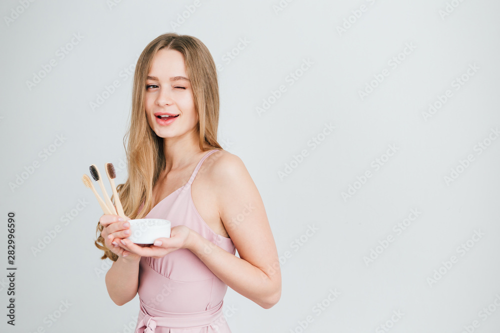 Girl holding a useful bamboo toothbrush and a jar of tooth powder Girl holding a useful bamboo toothbrush and a jar of tooth powder