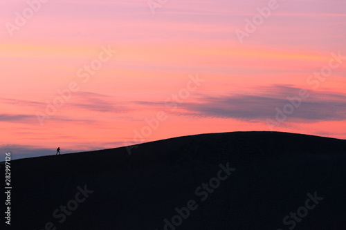 One sunset hiker walking sand dune crest © PiLensPhoto
