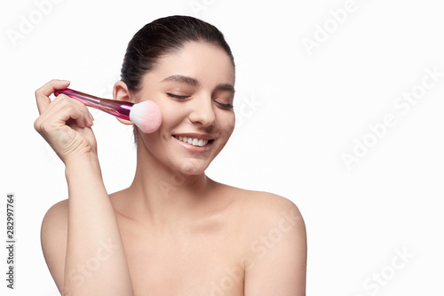 Cheerful model applying face powder