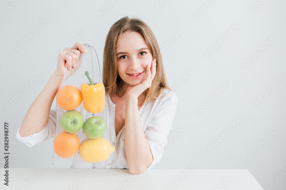Girl packs the vegetables and fruits in a reusable cloth bag Girl packs the vegetables and fruits in a reusable cloth bag