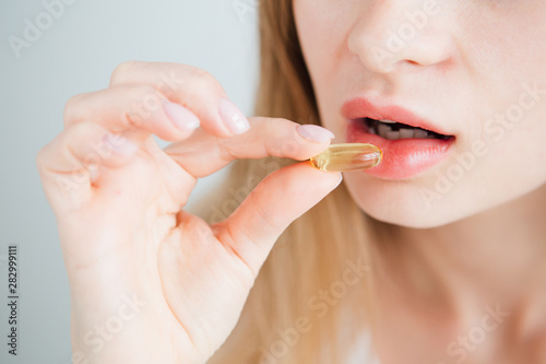 young beautiful girl puts a pill in her mouth close-up