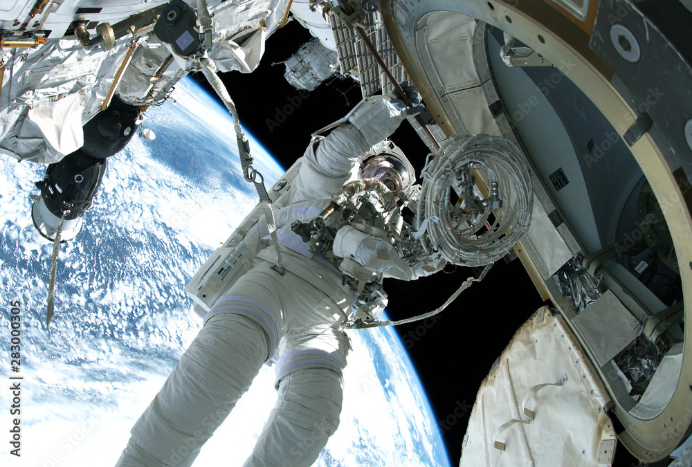The astronaut in a space suit, in an outer space, is engaged in repair of the space station.  Elements of this image were furnished by NASA - obrazy, fototapety, plakaty 