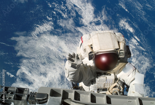 Fototapeta Naklejka Na Ścianę i Meble -  The astronaut in a space suit, waves a hand, at the space station, in an outer space.  Elements of this image were furnished by NASA
