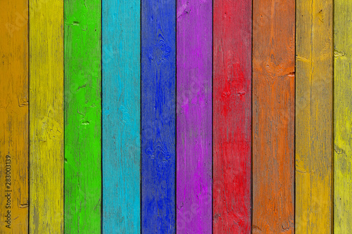 Close-up of a rainbow wooden wall or fence painted a very long time and the paint peeled off. Fun background for kids decor and design.