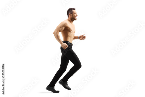 Young shirtless man running in trousers and shoes