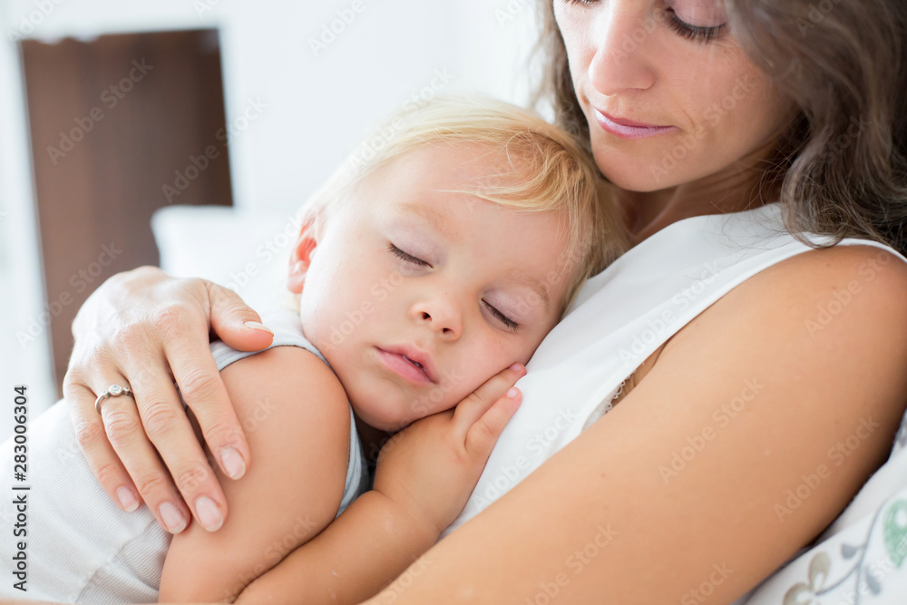 Young mother lying in bed with her sleeping toddler baby boy Young mother lying in bed with her sleeping toddler baby boy