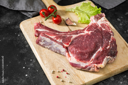 Raw beef meat on wooden Board on dark background
