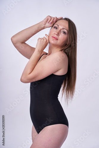 Beautiful girl in swimsuit posing against grey white background. Well-groomed skin.