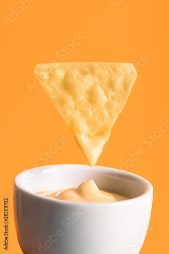 Картината върху платно crispy corn nacho with cheese sauce in bowl isolated on orange, Mexican cuisine