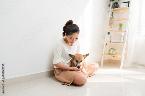 Attractive young Asian woman with her Corgi dog at home