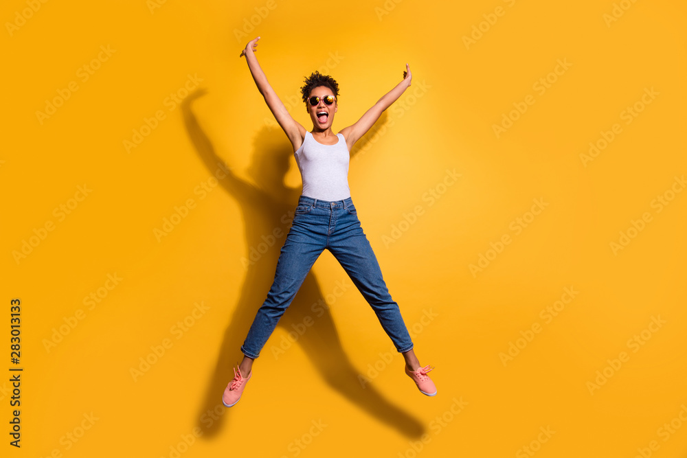 Full length body size photo beautiful she her dark skin excited lady jumping high scream shout yell yeah yes triumphant champion wear casual jeans denim tank-top isolated bright yellow background