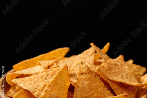 crispy tasty Mexican nachos in wooden bowl isolated on black