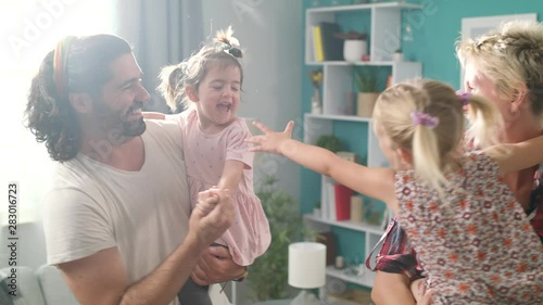 Mom and Dad are dancing with daughters in their arms at living room