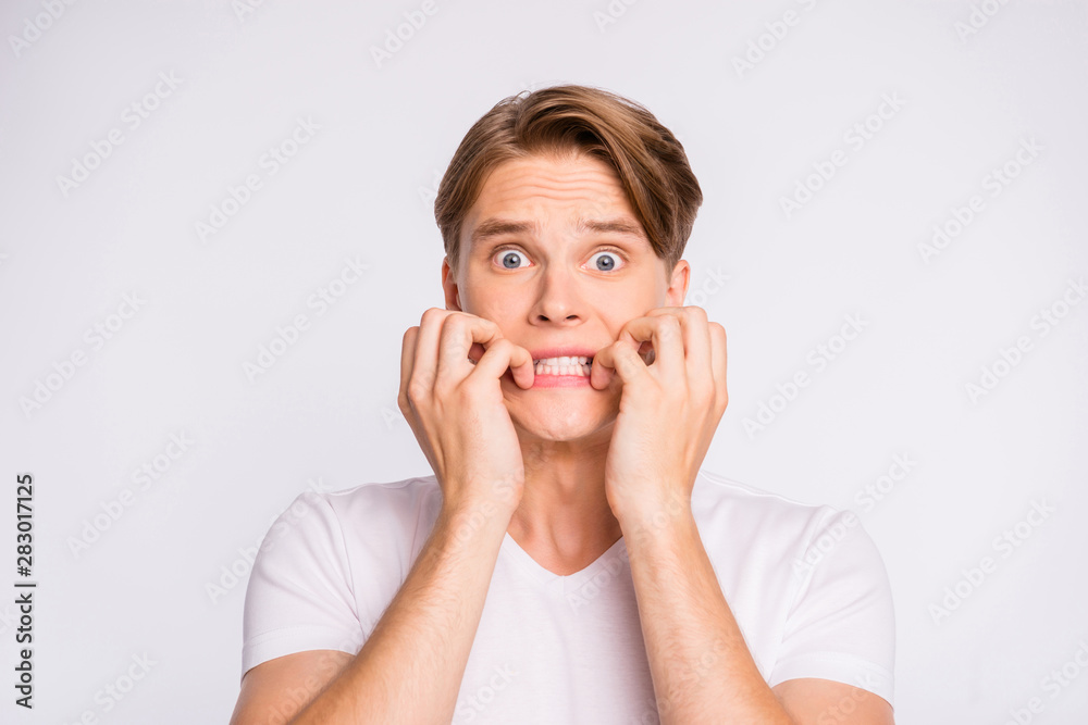 Teen guy with eyes full of fear biting arms wear casual outfit isolated on white background Teen guy with eyes full of fear biting arms wear casual outfit isolated on white background