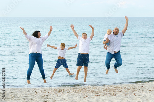 glückliche Familie springt am Strand in die Luft