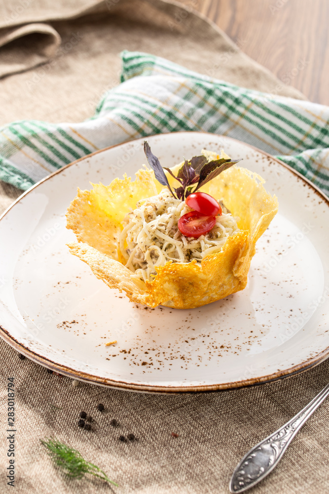 Fresh salad with cheese and walnut in edible melted cheese bowl on grey tablecloth Fresh salad with cheese and walnut in edible melted cheese bowl on grey tablecloth