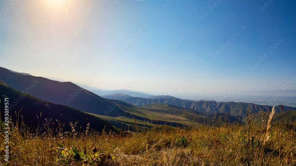 Fototapeta premium Panorama of a mountain valley in summer, aerial view. Fairytale sunset over the mountain peaks, amazing nature, summer in the mountains. Travel, tourism. beautiful background picture of nature