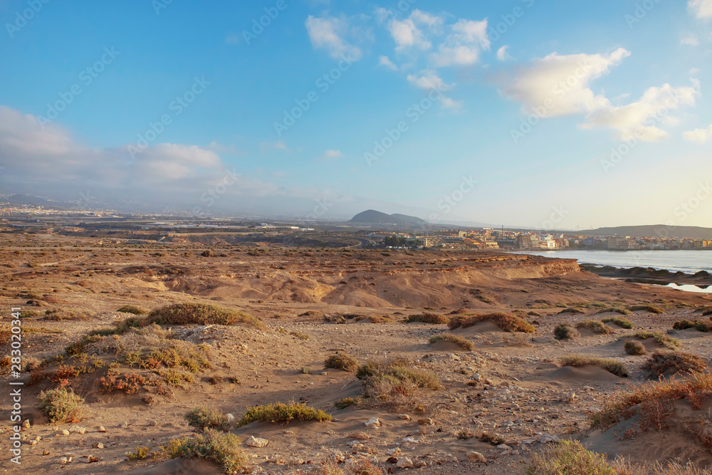 Early morning views from Montana Roja Special Natural Reserve, one of the best samples of inorganic sand habitats on the island of Tenerife towards the quaint town of El Medano, Canary Islands, Spain