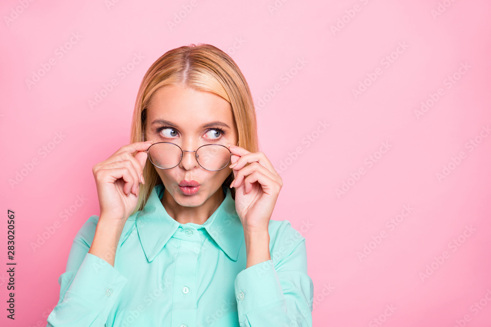 Portrait of astonished girl looking touching her specs wearing mint colored shirt isolated over pink background Portrait of astonished girl looking touching her specs wearing mint colored shirt isolated over pink background