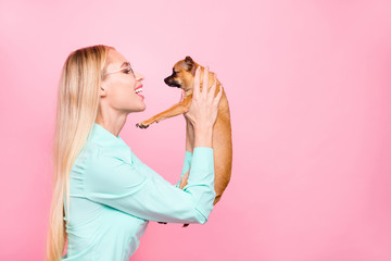 Profile side photo of cute lady holding her chihuahua speaking wearing mint-colored shirt isolated over pink background