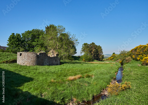 An abandoned Stone ruin with an unusual curved end wall lies in a small Field within a Valley with a small stream and views of the Angus Glens. Guthrie, Scotland. photo