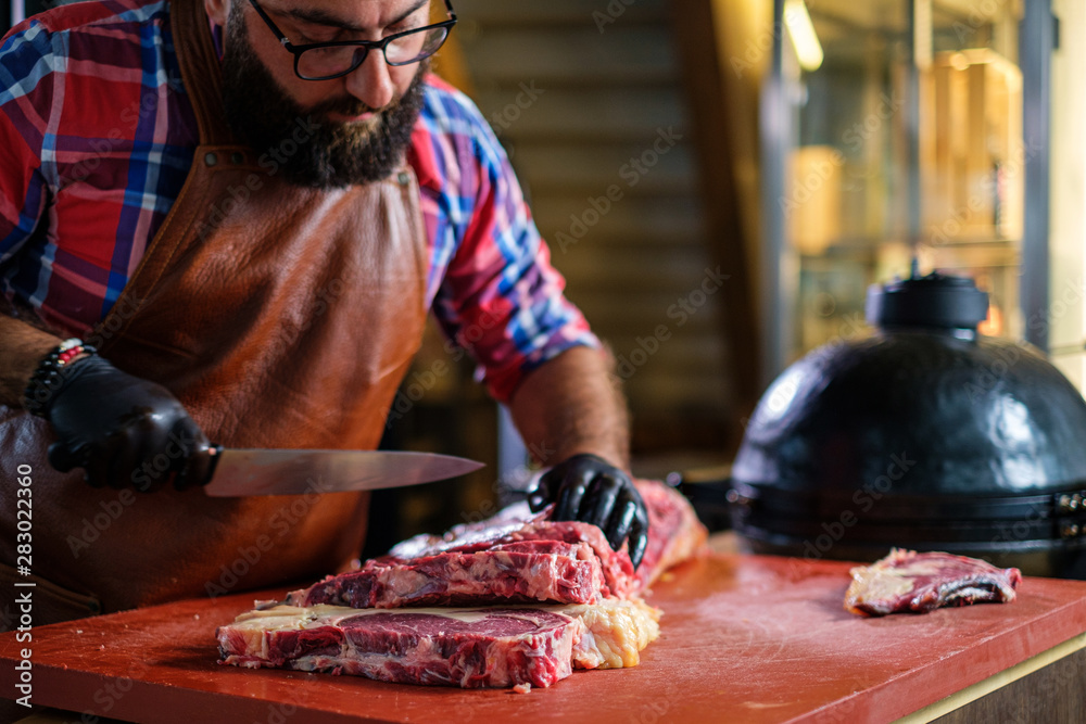 Chef cutting beef steakes in a restaurant Chef cutting beef steakes in a restaurant