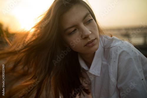 Portrait of young sad woman with loose hair at sunset.