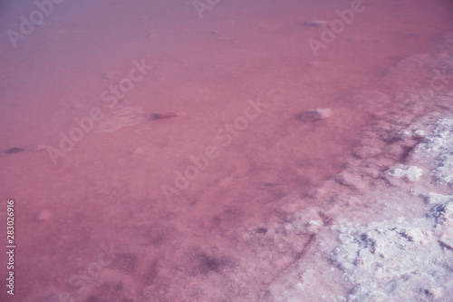 Textured of different shapes of rocks of salt in a pink water basin.