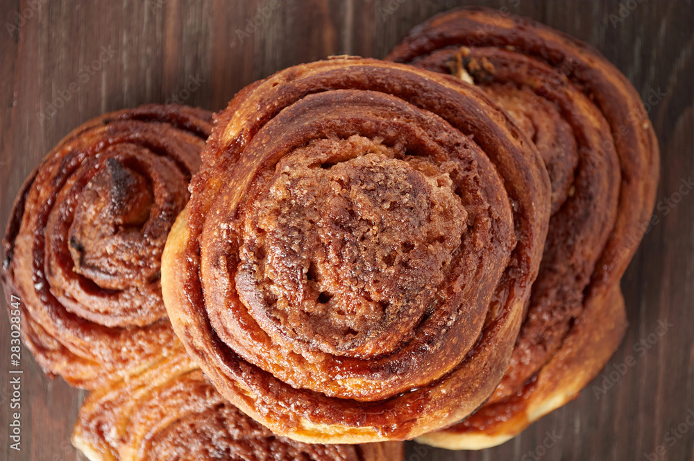Fototapeta premium Homemade sweet cinnamon buns with sugar on wooden cut board