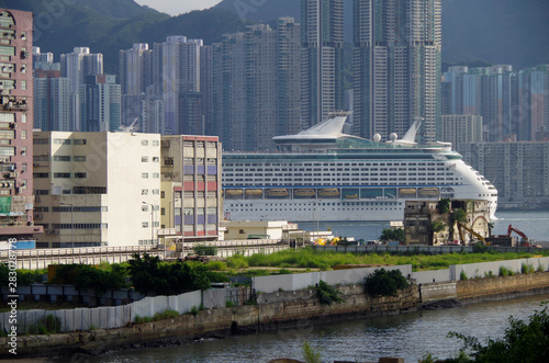 Teil von grossem Royal Caribbean Kreuzfahrtschiff Explorer of the Seas im Hafen von Hong Kong vor Skyline von Shau Kei Wan und Teilen von Yau Tong Industrial City Park Industrieanlagen photo