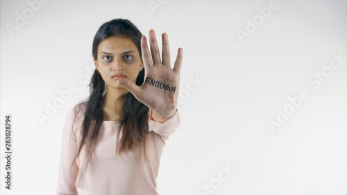 Young beaten up girl fighting against domestic violence - stop hurting women. Indian woman extending her hand and showing the word 'enough' to stop violence against her - refusing gestures concept photo