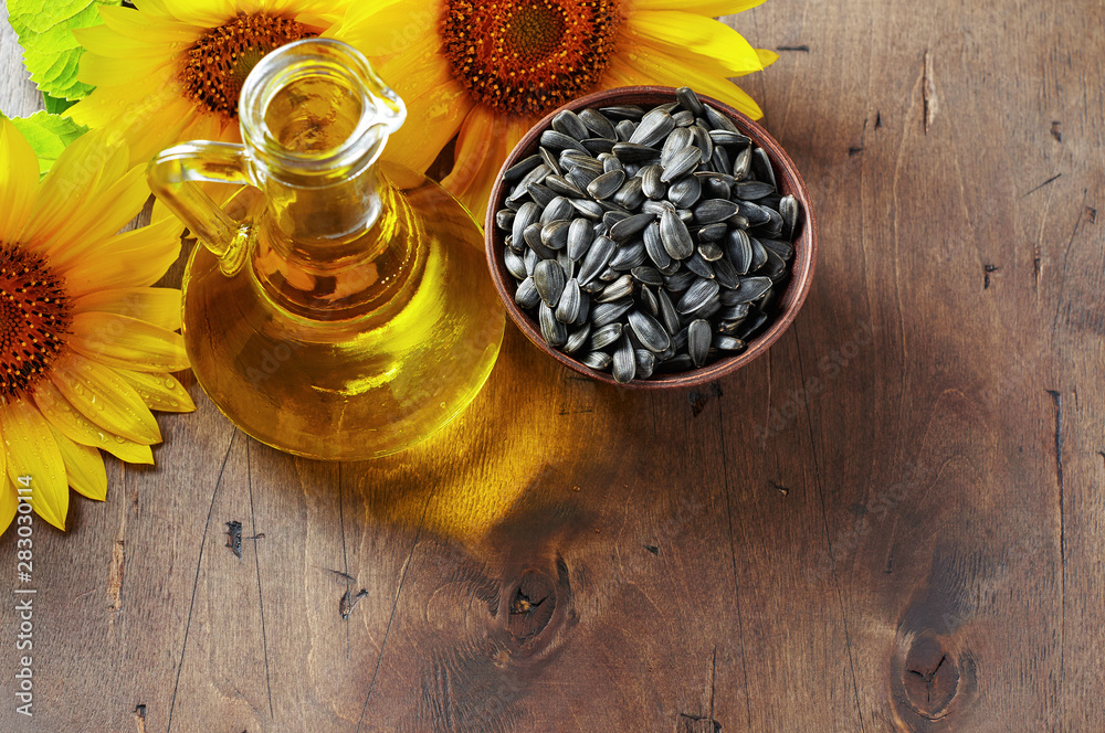 Glass bottle of sunflower oil with seeds and flowers. Close up top view with copy space