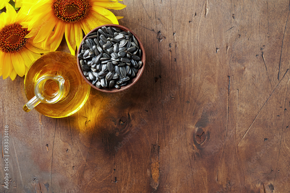 Glass bottle of sunflower oil with seeds and flowers. Close up top view with copy space