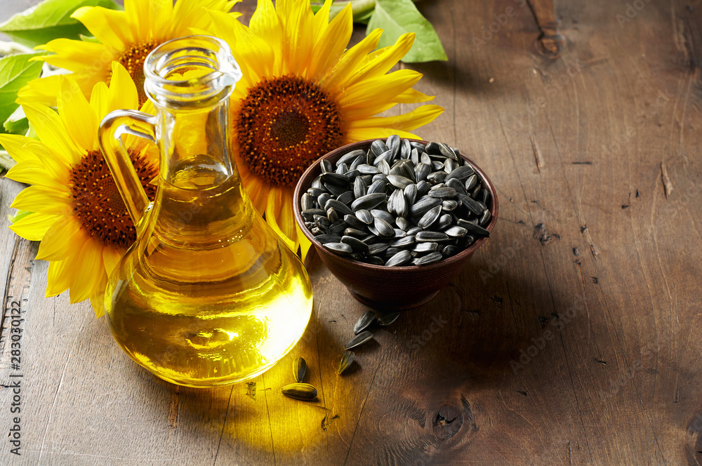 Glass bottle of sunflower oil with seeds and flowers. Close up view