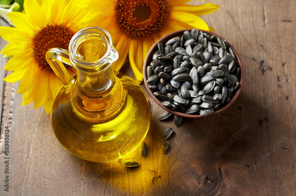 Glass bottle of sunflower oil with seeds and flowers. Close up top view with copy space