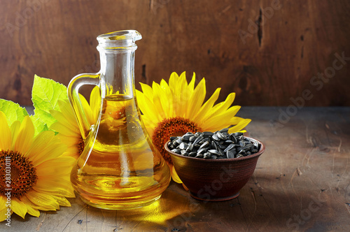 Glass bottle of sunflower oil with seeds and flowers. Close up view with copy space