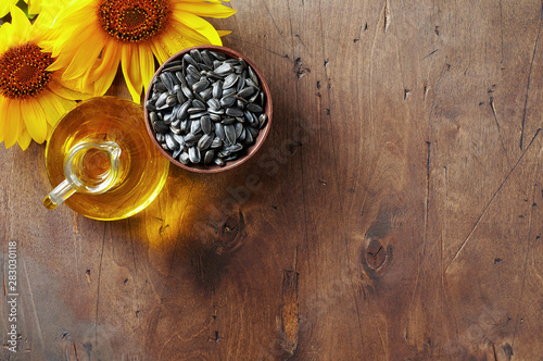 Obraz na płótnie Glass bottle of sunflower oil with seeds and flowers. Close up top view with copy space w salonie