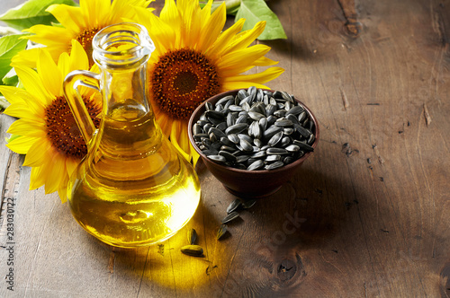 Obraz na płótnie Glass bottle of sunflower oil with seeds and flowers. Close up view w salonie