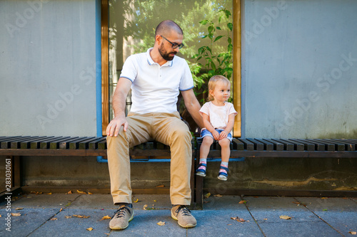father and his daughter sitting on a bench