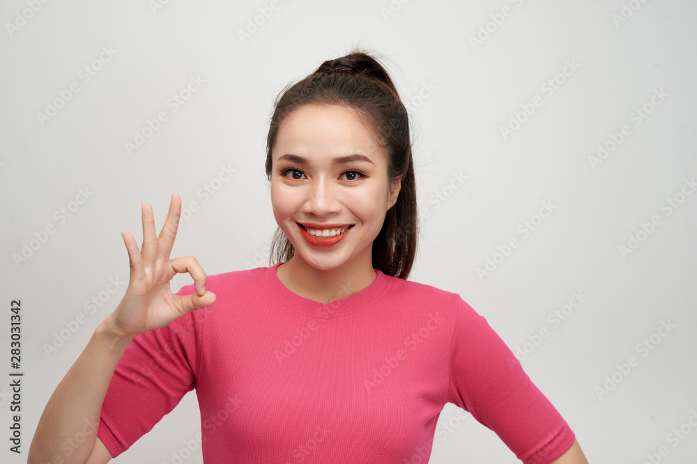 Portrait of a smiling woman showing ok sign with fingers isolated on a white background Portrait of a smiling woman showing ok sign with fingers isolated on a white background