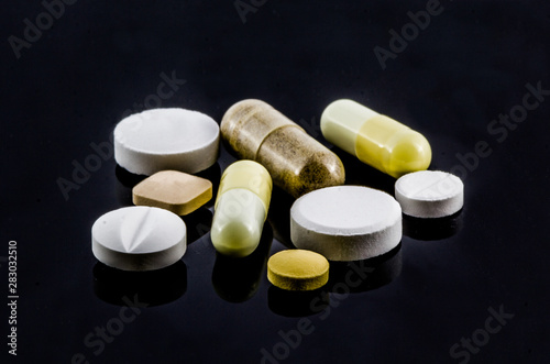 A lot of capsules and tablets pill on black
