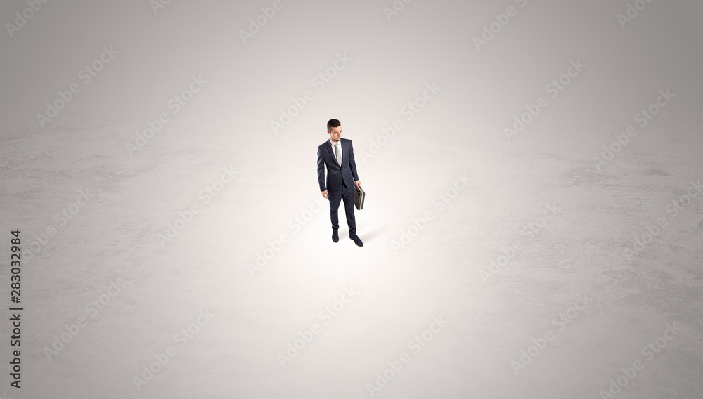 Young businessman standing alone in the middle of an empty space Young businessman standing alone in the middle of an empty space