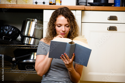 Hübsche junge Frau liest ein Buch in der Küche. 