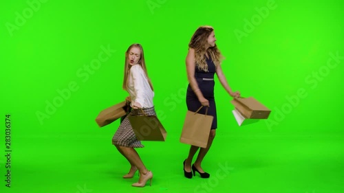 Extremely happy fashionable shoppers walk and dance from side to side over green screen.